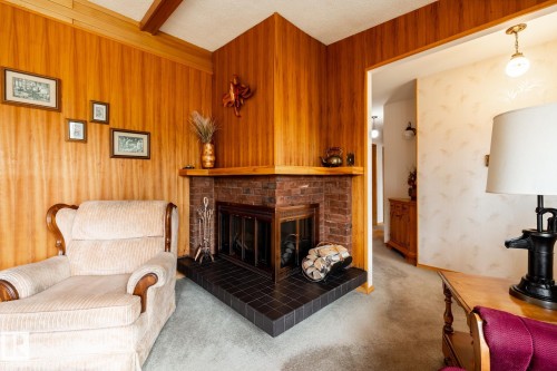 Corner fireplace featuring a brick surround and black tile hearth - 8612 68A Street, Edmonton, AB - Indoor Photo Showing Living Room With Fireplace