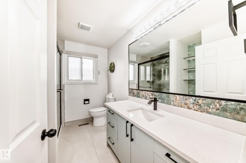 Contemporary bathroom vanity featuring a rectangular undermount sink, matte black faucet, and a large wall-mounted mirror with integrated lighting - 2039 48 Street, Edmonton, AB - Indoor Photo Showing Bathroom