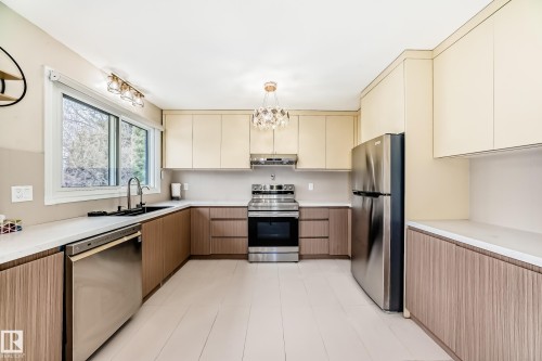 Modern kitchen featuring dual-tone cabinetry, stainless steel appliances, white countertops, and light plank flooring - 2039 48 Street, Edmonton, AB - Indoor Photo Showing Kitchen With Stainless Steel Kitchen