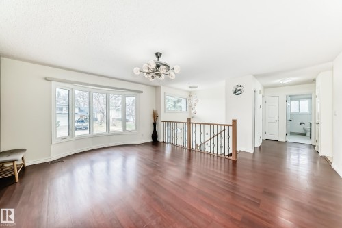 Expansive living area featuring rich wood-finish flooring and a prominent bay window - 2039 48 Street, Edmonton, AB - Indoor