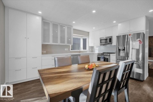 Kitchen with stainless steel appliances, glass insert cabinets, a textured ceiling, tasteful backsplash, and white cabinets - 3515 20 Avenue, Edmonton, AB - Indoor