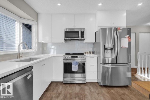 Kitchen with appliances with stainless steel finishes, white cabinetry, a textured ceiling, tasteful backsplash, and dark wood-type flooring - 3515 20 Avenue, Edmonton, AB - Indoor Photo Showing Kitchen With Stainless Steel Kitchen