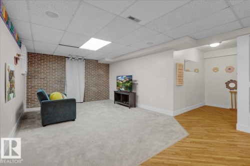 Living area with light wood-type flooring, a drop ceiling, and light carpet - 3515 20 Avenue, Edmonton, AB - Indoor