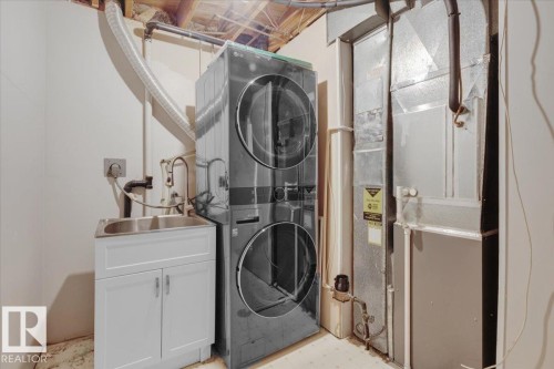 Washroom featuring estacked washer and dryer, heating unit, and light flooring - 3515 20 Avenue, Edmonton, AB - Indoor Photo Showing Laundry Room