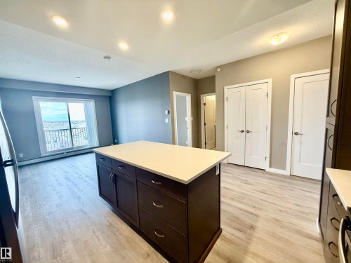 Kitchen island featuring a light-toned countertop and dark wood-finish cabinetry - 437 5504 Schonsee Drive, Edmonton, AB - Indoor