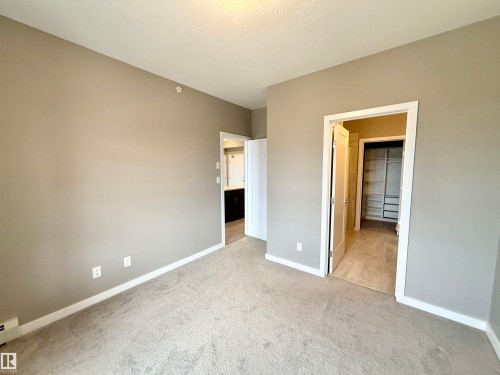 Neutral-toned bedroom featuring wall-to-wall carpeting and crisp white trim - 437 5504 Schonsee Drive, Edmonton, AB - Indoor Photo Showing Other Room