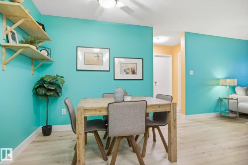 Dining area featuring wood-finish flooring, a ceiling fan with integrated lighting, built-in shelving, and light-colored baseboards - 103 10732 86 Avenue, Edmonton, AB - Indoor Photo Showing Dining Room