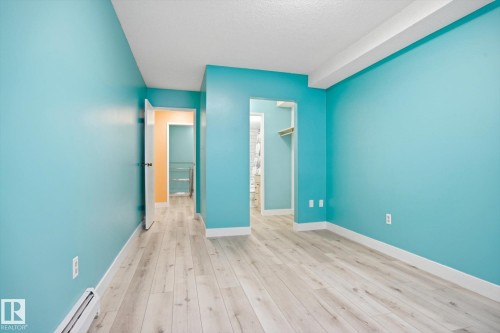 Bright interior space featuring light wood-finish flooring and vibrant blue walls - 103 10732 86 Avenue, Edmonton, AB - Indoor Photo Showing Other Room