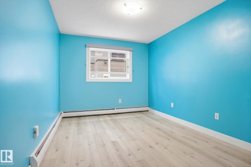 Interior space featuring light wood-finish flooring, a white trim baseboard, and a window with a roller shade - 103 10732 86 Avenue, Edmonton, AB - Indoor Photo Showing Other Room