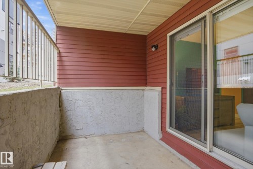 Patio featuring concrete flooring, a stucco half-wall, and a sliding glass door with an integrated screen - 103 10732 86 Avenue, Edmonton, AB - Outdoor With Exterior