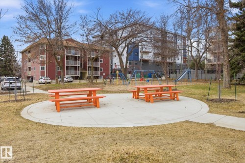 Central concrete patio featuring two orange picnic tables - 103 10732 86 Avenue, Edmonton, AB - Outdoor