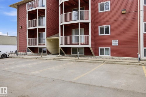 Exterior of a multi-story building featuring red horizontal siding, multiple balconies with white railings, and white-framed windows - 103 10732 86 Avenue, Edmonton, AB - Outdoor With Exterior