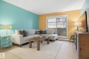 Living area with light wood-finish flooring, accent walls, and a sliding glass door - 103 10732 86 Avenue, Edmonton, AB  - Indoor Photo Showing Living Room 