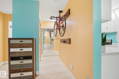 Light wood-finish flooring extends through the hallway with white baseboards - 103 10732 86 Avenue, Edmonton, AB - Indoor Photo Showing Other Room