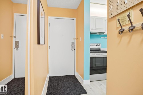 Entryway featuring a white solid-core door, a full-length mirror, and light peach wall finishes - 103 10732 86 Avenue, Edmonton, AB - Indoor Photo Showing Other Room