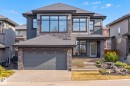 Contemporary two-story residence featuring a dark gray roof, stone facade accents, an attached garage, a multi-pane front door, and a tiered front pathway - 1313 Hainstock Way, Edmonton, AB  - Outdoor With Facade 