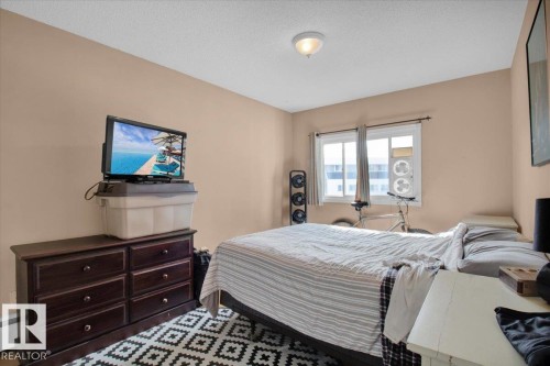 This room features neutral-toned walls, a window providing natural light, and a patterned area rug - 412 2908 116A Avenue, Edmonton, AB - Indoor Photo Showing Bedroom
