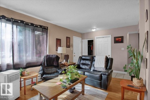 The living area features hardwood floors and a window with sheer curtains - 412 2908 116A Avenue, Edmonton, AB - Indoor Photo Showing Living Room