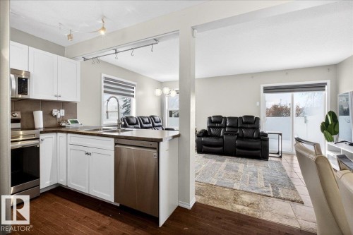 Kitchen featuring open floor plan, white cabinetry, dark countertops, stainless steel appliances, and a peninsula - 47 230 Edwards Drive, Edmonton, AB - Indoor Photo Showing Kitchen