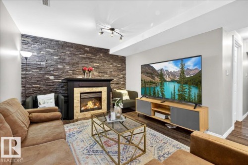 Family room featuring a glass covered fireplace and wood finished floors - 47 230 Edwards Drive, Edmonton, AB - Indoor Photo Showing Living Room With Fireplace