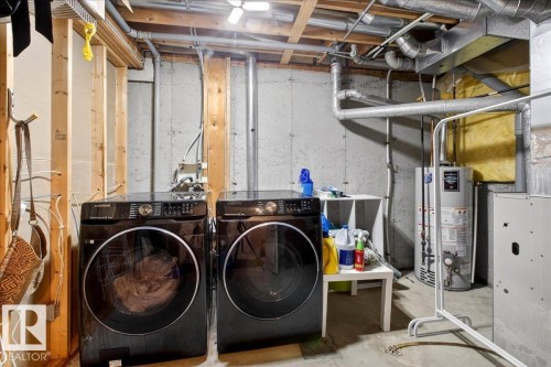 Laundry area featuring water heater, concrete floors, heating unit, and washer and clothes dryer - 47 230 Edwards Drive, Edmonton, AB - Indoor Photo Showing Laundry Room