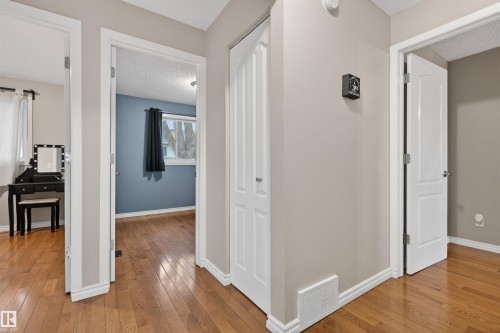 Hallway featuring wood-finish flooring, light neutral wall tones, and white trim - 17120 103 Street, Edmonton, AB - Indoor Photo Showing Other Room
