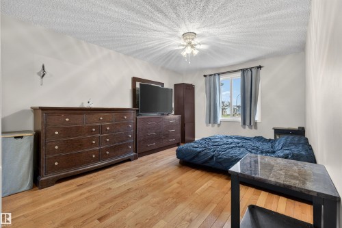 Light wood-finish flooring complements neutral wall tones and a textured ceiling - 17120 103 Street, Edmonton, AB - Indoor Photo Showing Bedroom