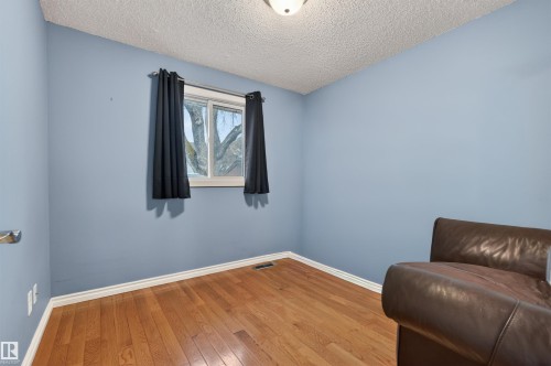 Bright room featuring a window with natural light, wood-finish flooring, light blue walls, and white trim - 17120 103 Street, Edmonton, AB - Indoor Photo Showing Other Room