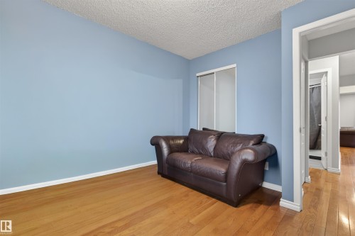 Room featuring light blue walls, wood-finish flooring, white baseboards, and a sliding window with roller shades - 17120 103 Street, Edmonton, AB - Indoor