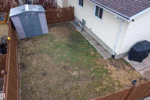 Fenced backyard featuring a storage shed, concrete patio area, and mature perimeter trees - 17120 103 Street, Edmonton, AB - Outdoor