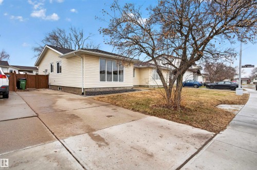 Exterior featuring light-colored siding, multiple windows including a prominent bay window, a concrete driveway, and a front yard with mature trees - 17120 103 Street, Edmonton, AB - Outdoor