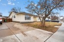 Exterior featuring light-colored siding, multiple windows including a prominent bay window, a concrete driveway, and a front yard with mature trees - 17120 103 Street, Edmonton, AB  - Outdoor 