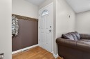 Entryway featuring wood-finish flooring, a white paneled door with an arched window, and a built-in wood coat rack with multiple hooks - 17120 103 Street, Edmonton, AB  - Indoor 