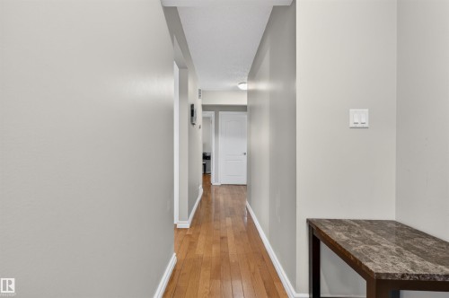 Hallway featuring wood-finish flooring, light gray wall paint, white baseboards, and a recessed ceiling light fixture - 17120 103 Street, Edmonton, AB - Indoor Photo Showing Other Room