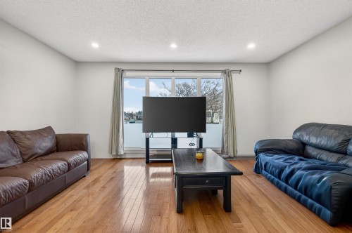 Spacious living area featuring expansive windows, wood-finish flooring, recessed lighting, and light-toned wall finishes - 17120 103 Street, Edmonton, AB - Indoor