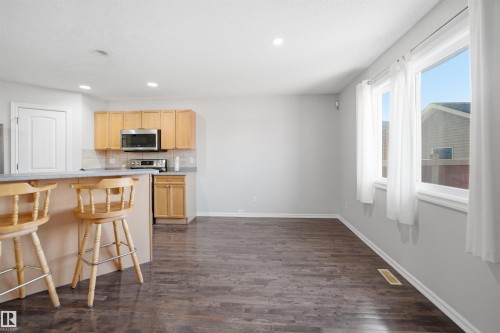 Bright open-concept living space featuring wood-finish flooring, recessed lighting, and a kitchen area with light wood cabinetry - 1124 37A Avenue, Edmonton, AB - Indoor Photo Showing Kitchen