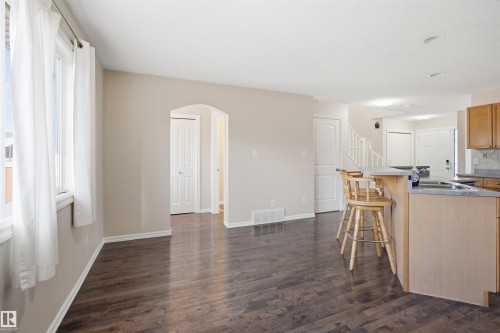 Open-concept living space featuring wood-finish flooring, an arched doorway, and an eat-at kitchen island with a stone-look countertop - 1124 37A Avenue, Edmonton, AB - Indoor Photo Showing Kitchen