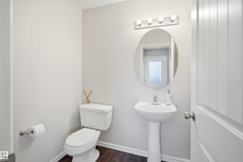 Pedestal sink with chrome faucet, an oval vanity mirror, and a four-light fixture - 1124 37A Avenue, Edmonton, AB - Indoor Photo Showing Bathroom
