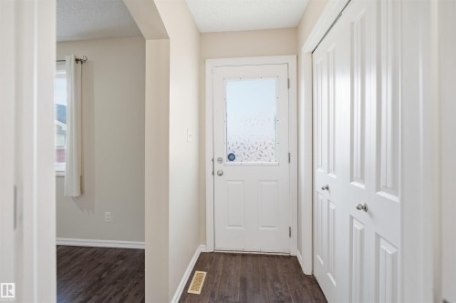 Entryway featuring dark wood-finish flooring, a white door with decorative glass inlay, and white bi-fold closet doors - 1124 37A Avenue, Edmonton, AB - Indoor Photo Showing Other Room