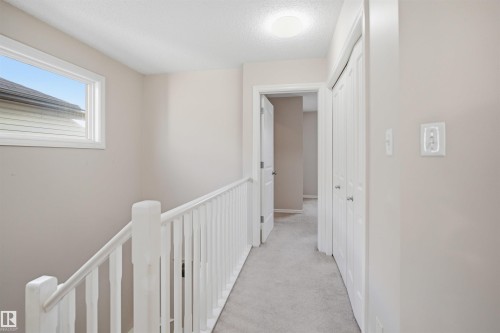 Light gray carpeted hallway with a white spindle railing and a window - 1124 37A Avenue, Edmonton, AB - Indoor Photo Showing Other Room