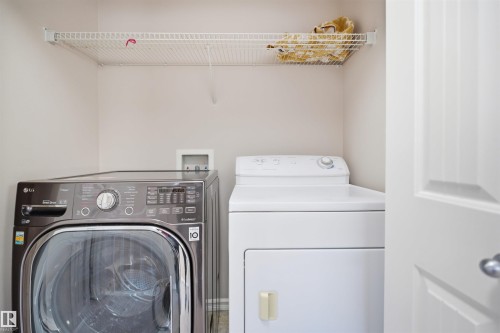 Dedicated laundry area featuring a front-load washer, top-load dryer, and a wire storage shelf - 1124 37A Avenue, Edmonton, AB - Indoor Photo Showing Laundry Room