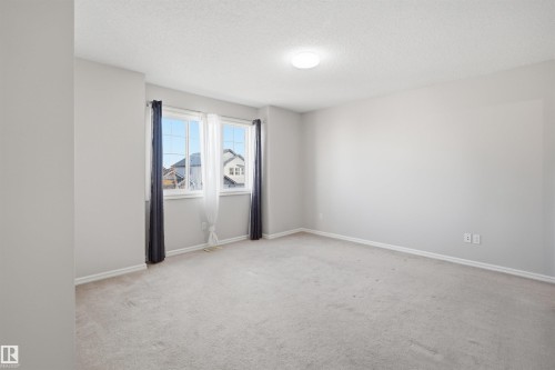 Carpeted room featuring two large windows with white trim, a flush-mount ceiling light, light gray wall paint, and white baseboards - 1124 37A Avenue, Edmonton, AB - Indoor Photo Showing Other Room