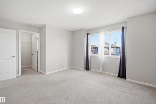 Spacious room with light gray carpeting and walls, featuring a large window with white framing - 1124 37A Avenue, Edmonton, AB - Indoor Photo Showing Other Room