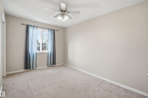 Bright interior room featuring a window with vertical blinds, a ceiling fan with integrated lighting, textured ceiling finish, and neutral-toned carpeting - 1124 37A Avenue, Edmonton, AB - Indoor Photo Showing Other Room