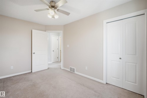 Carpeted room featuring a ceiling fan with integrated lighting, a paneled bifold closet, and painted trim - 1124 37A Avenue, Edmonton, AB - Indoor Photo Showing Other Room