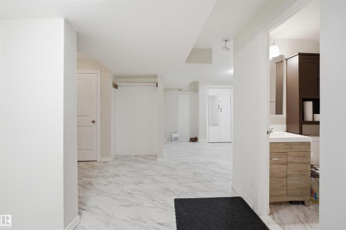 Open concept lower level featuring white walls and marble-look tile flooring - 1124 37A Avenue, Edmonton, AB - Indoor Photo Showing Other Room