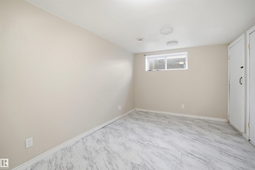 Room featuring light-toned walls, white marble-look flooring, a window with horizontal blinds, and two built-in storage cabinets - 1124 37A Avenue, Edmonton, AB - Indoor Photo Showing Other Room