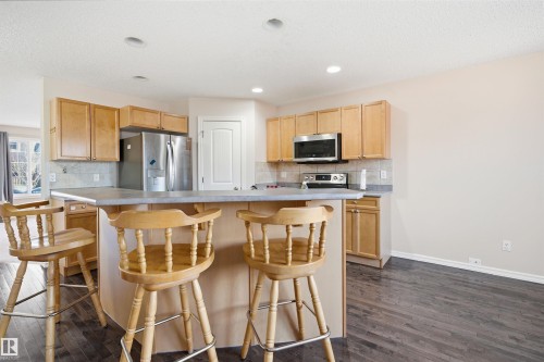Kitchen featuring light wood cabinetry, stainless steel appliances, a tiled backsplash, recessed lighting, and wood-finish flooring - 1124 37A Avenue, Edmonton, AB - Indoor Photo Showing Kitchen