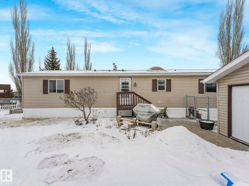 Rear exterior of a single-story residence featuring tan horizontal siding, white trim, and brown window shutters - 151 3400 48 Street, Stony Plain, AB - Outdoor With Exterior