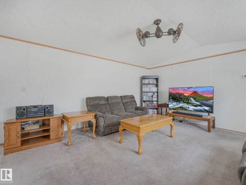 Spacious living area featuring carpet flooring, white walls, and a decorative ceiling fixture - 151 3400 48 Street, Stony Plain, AB - Indoor Photo Showing Living Room